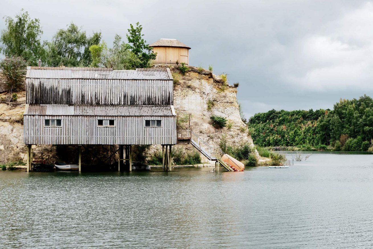 Rustic lakeside boathouse on stilts with wooden steps leading into Buckland Lake – photo by Rachel Groom Photography